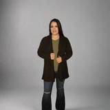 Woman wearing a black coat over a green shirt on a gray background