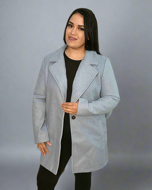 Woman wearing a light gray coat over a black outfit on a gray background