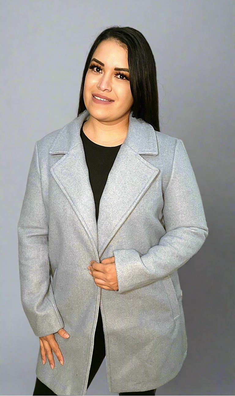 Woman wearing a light gray coat against a plain background