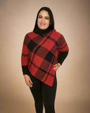 Woman wearing a red and black plaid sweater with black pants on a beige background