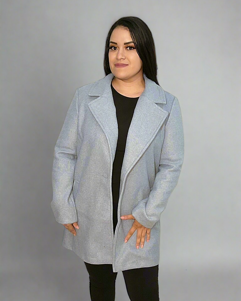 Woman wearing a light blue coat over a black outfit on a gray background