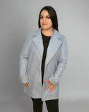 Woman wearing a light blue coat over a black outfit on a gray background