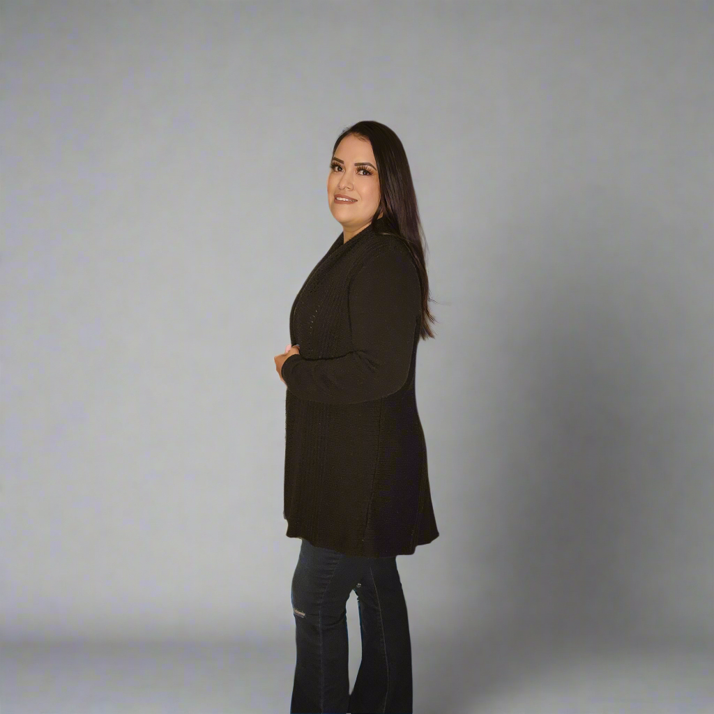 Woman wearing a black coat standing against a plain background