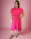 Woman wearing a bright pink dress against a pink background