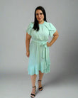 Woman wearing a light green dress against a plain background