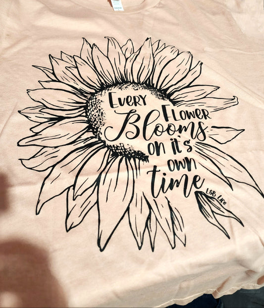 Beige t-shirt with a black sunflower design and text on a beige background