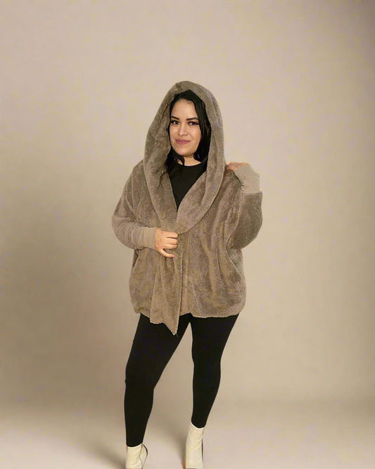 Woman wearing a beige hooded cardigan against a plain background