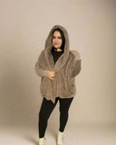 Woman wearing a beige hooded cardigan against a plain background