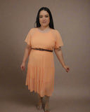 Woman wearing an orange dress with a white curtain background