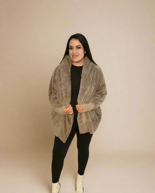Woman wearing a beige cardigan over a black top and pants on a beige background