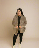 Woman wearing a beige cardigan over a black top and pants on a beige background
