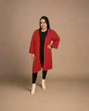 Woman wearing a red coat, black top, and white boots on a beige background